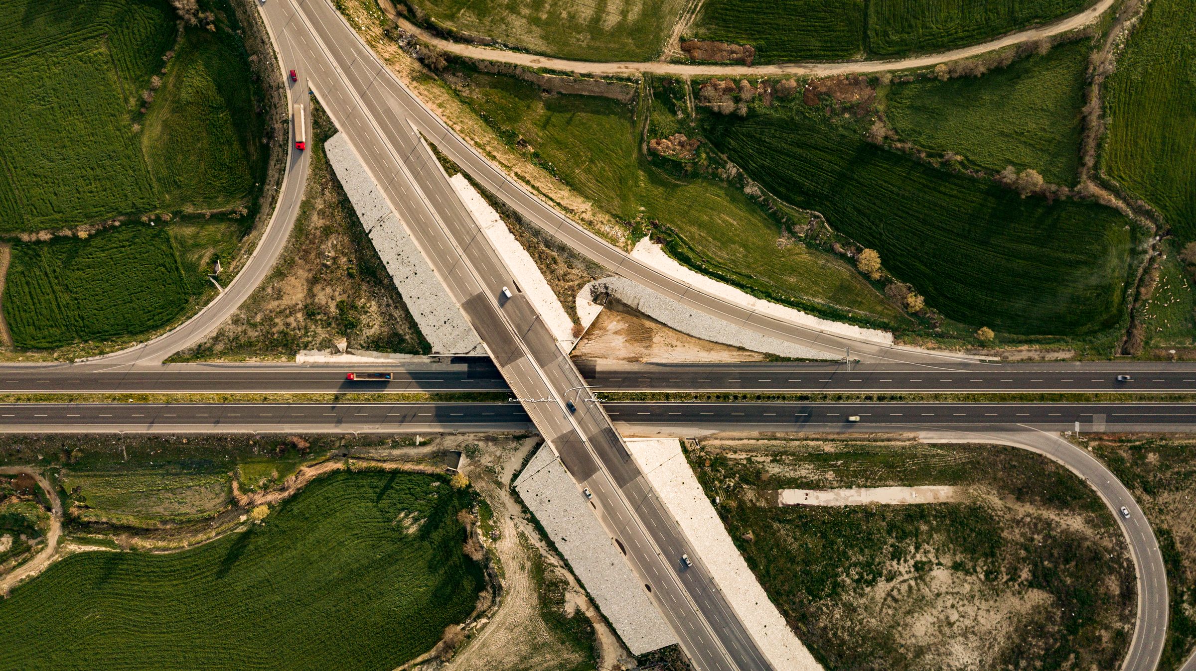 An aerial view of intersecting roads organized through green fields.